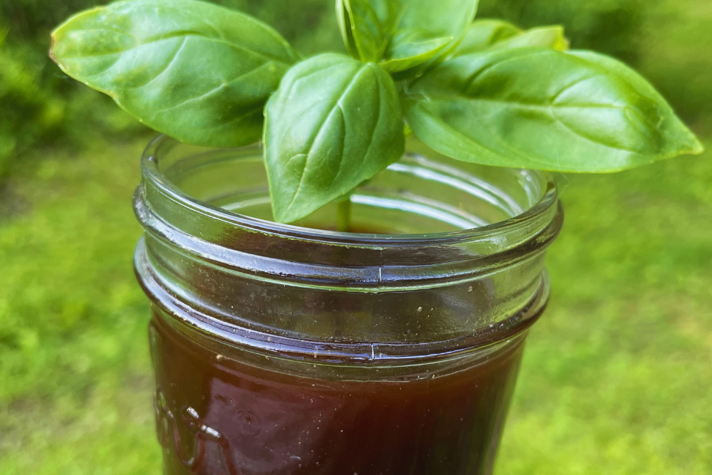 Strawberry Tops Syrup in mason jar garnished with basil