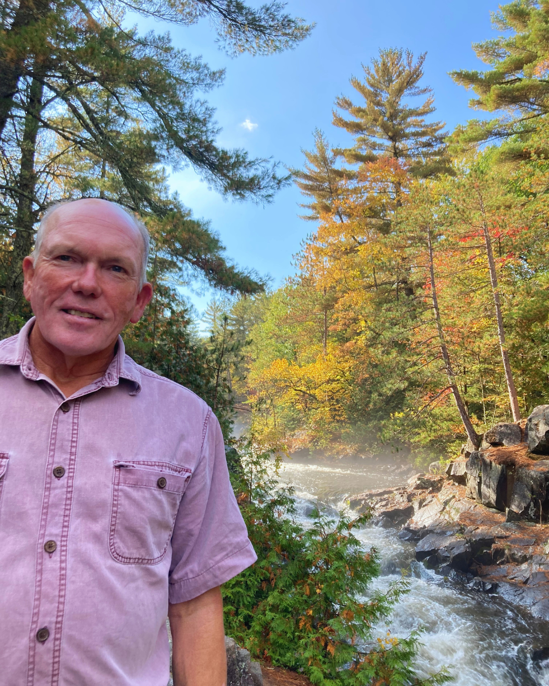 Rick Adamski standing in front of rushing river in woods
