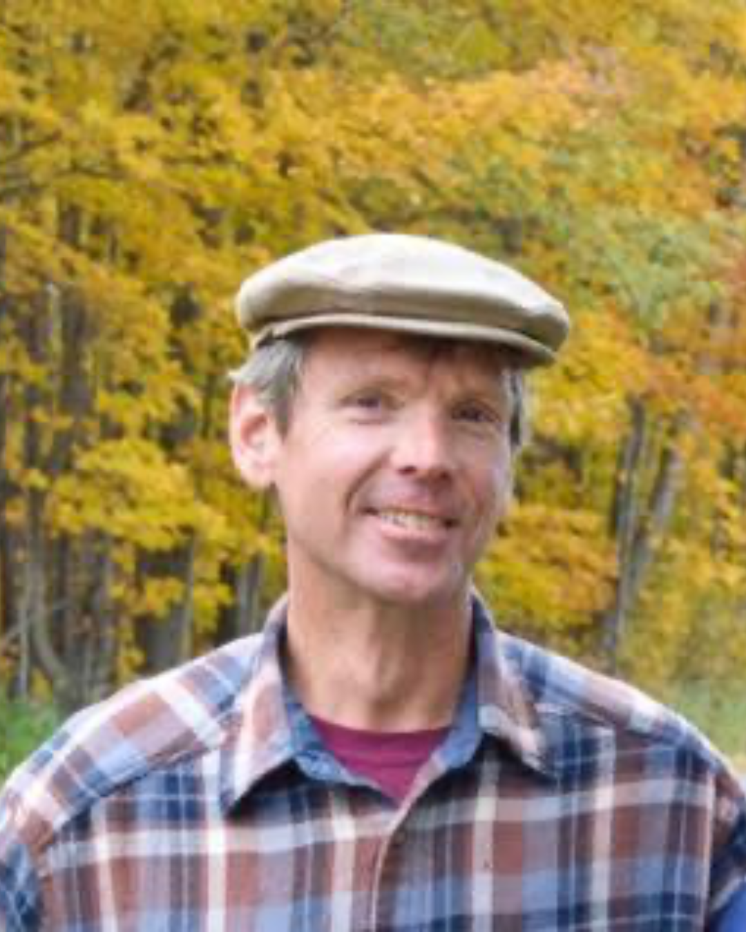 Steve smiling at camera with fall-color trees in the background