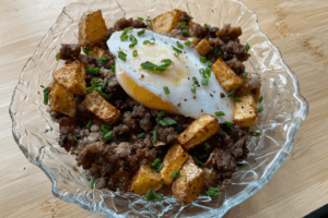 Ground beef and roasted potatoes mixed together topped with an over-easy egg and chives