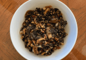 Bacon, Mushroom, and Barley Side Dish presented in a white bowl on a wooden table