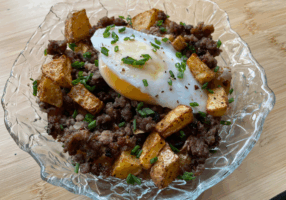 Ground beef and roasted potatoes mixed together topped with an over-easy egg and chives