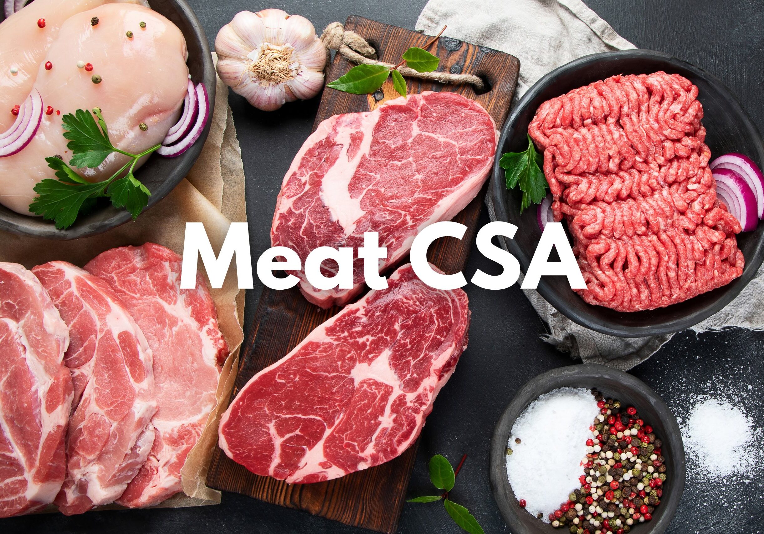 Variety of raw meats displayed on black surface including steaks, pork chops, chicken breasts, and ground meat