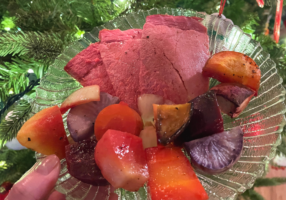 Glass plate with three slices of smoked ham and handful of chopped and roasted root vegetables