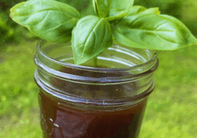 Strawberry Tops Syrup in mason jar garnished with basil